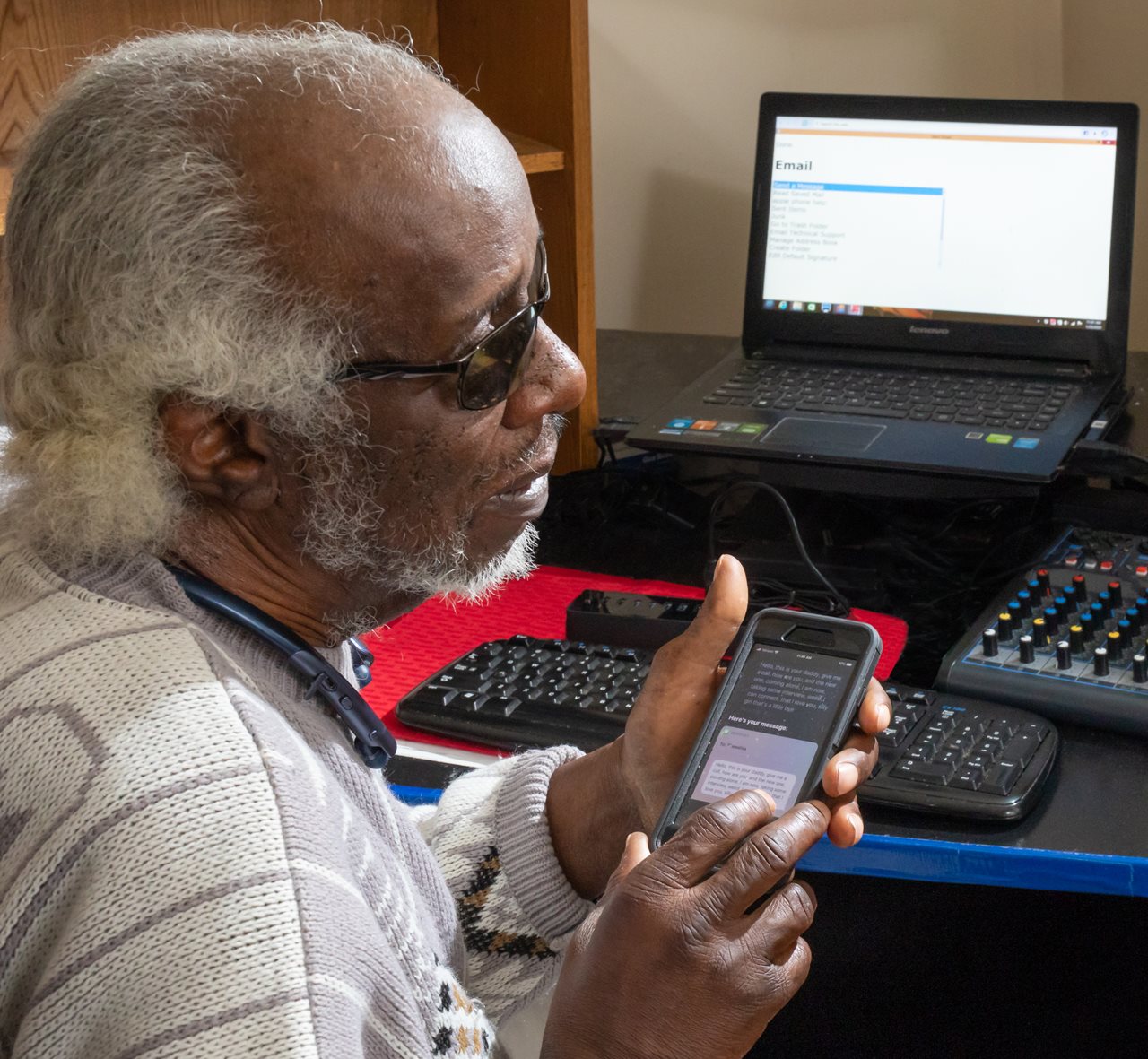 Ernest using a device that allows him to communicate with others using a phone and laptop.