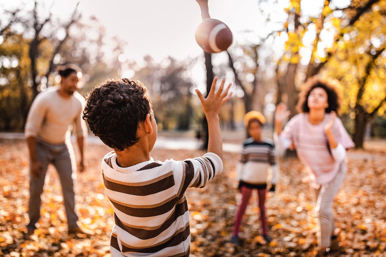 Family of four playing football in the backyard in Autumn.