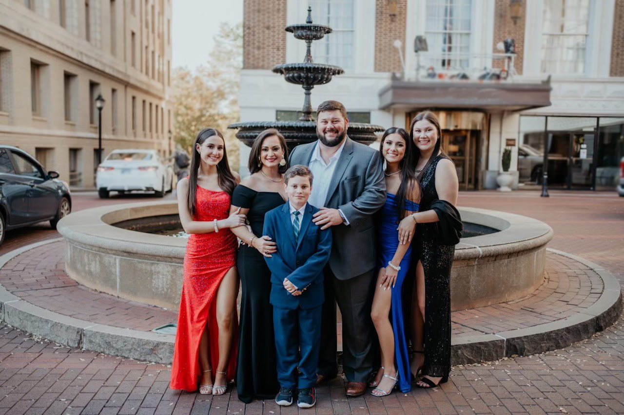 Marielle y su familia en ropa formal posando frente a una fuente.