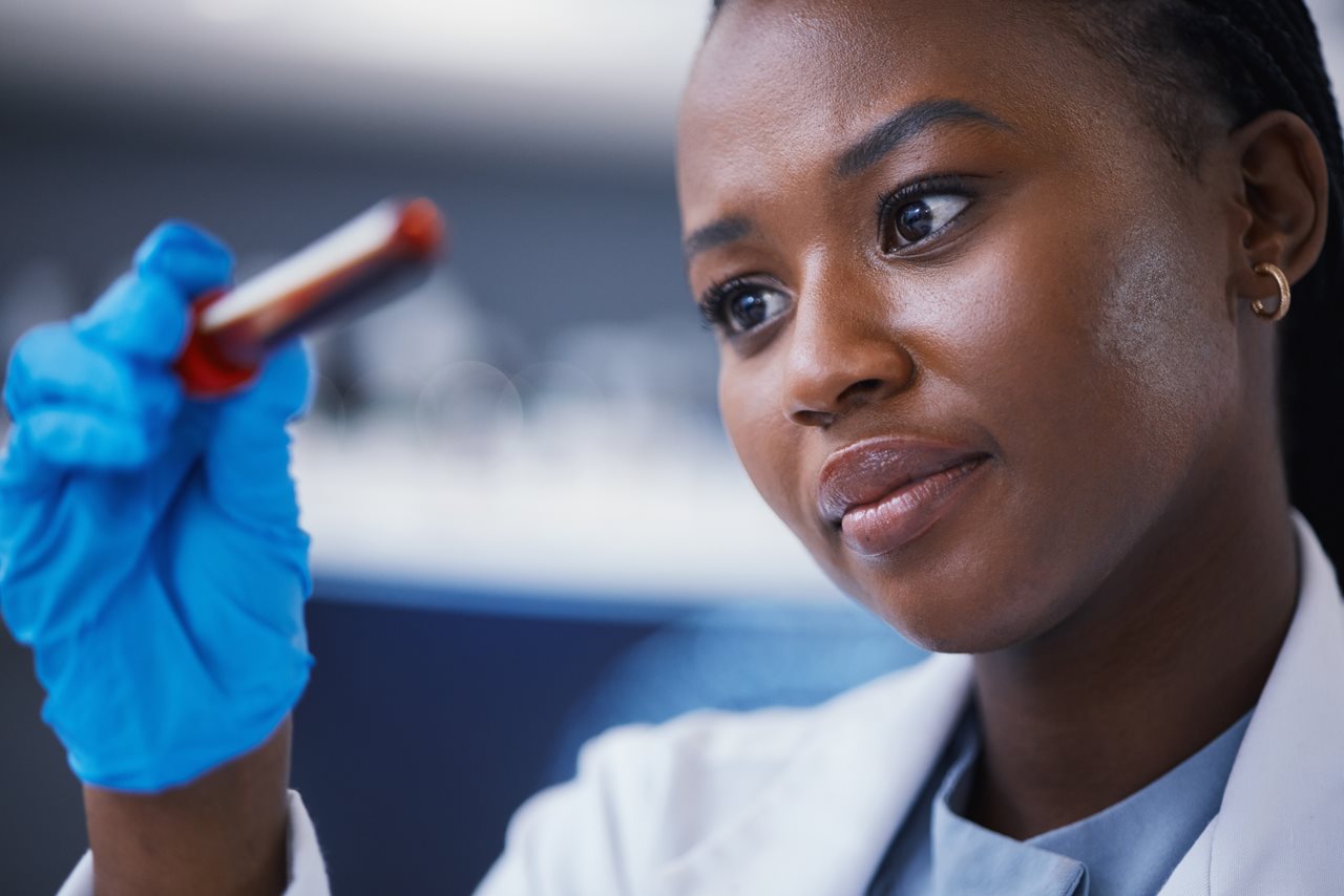 Doctora sosteniendo un tubo de ensayo de sangre que contiene material genético