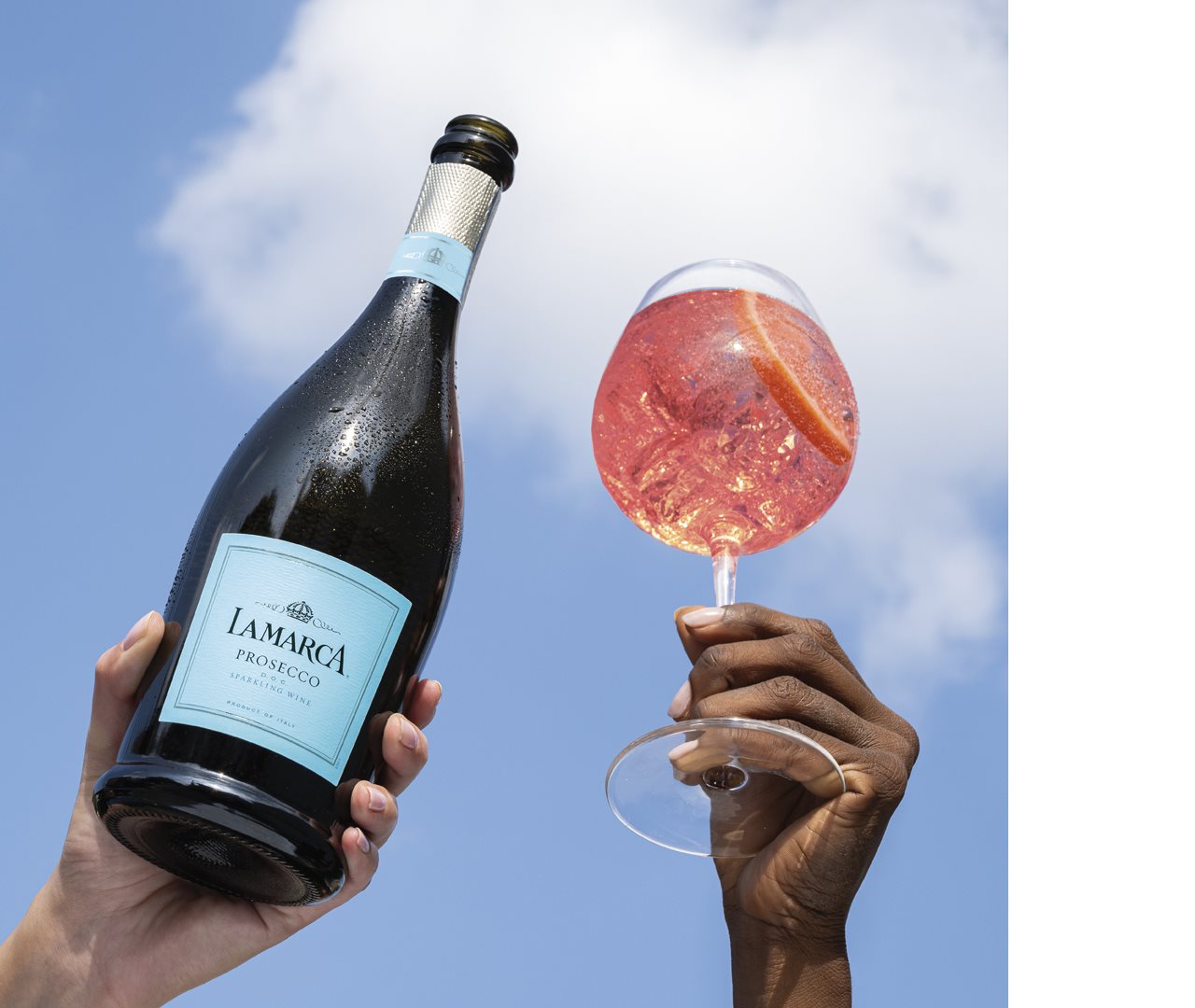 Bottle of LaMarca Prosecco and a filled glass raised to the sun.