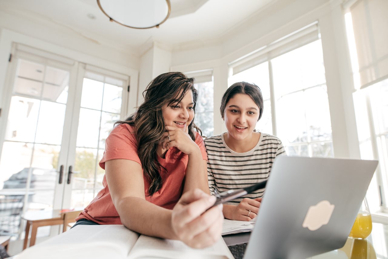 Mom and college-bound teen working on laptop in a four season porch.