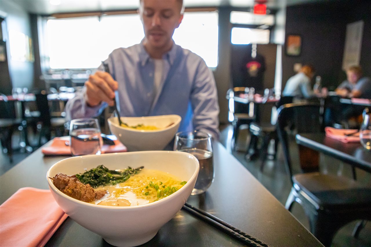 Man in a restaurant eating Bokujo Ramen with buffalo