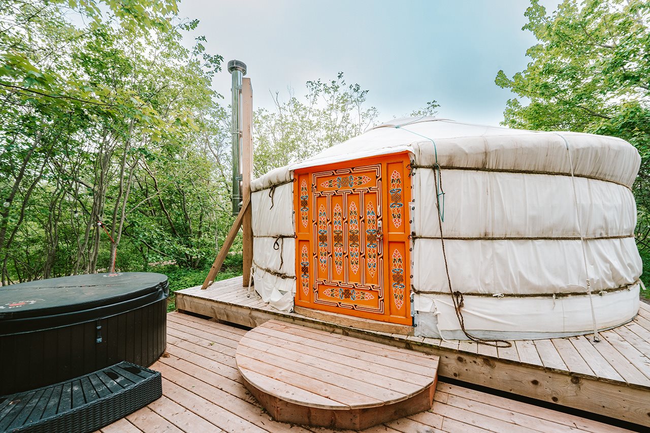 A Mongolian yurt with an ornate door and a chimney next to a jacuzzi