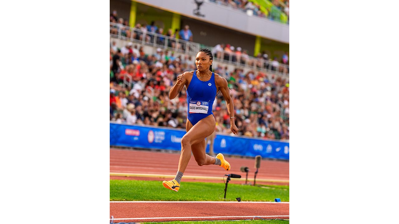 Athlete Tara Davis-Woodhall competing in a long jump event in a packed stadium