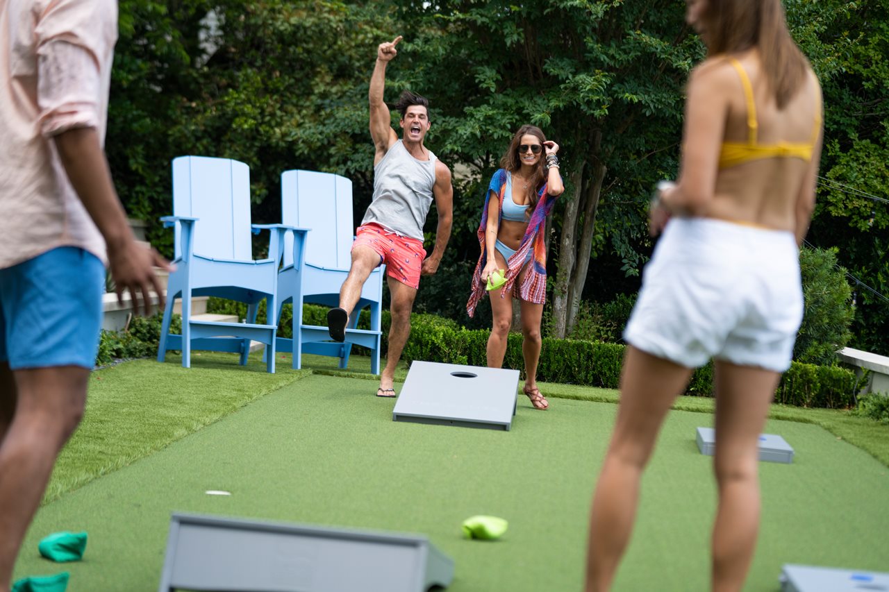group of people playing bean bags in the backyard.