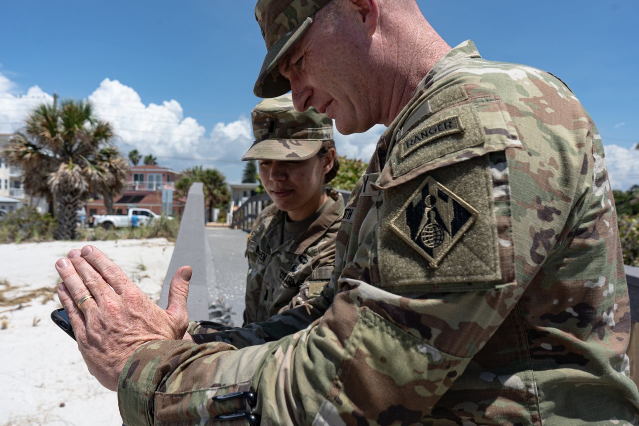 Two U.S. Army soldiers inspect smartphone photo they took on beach