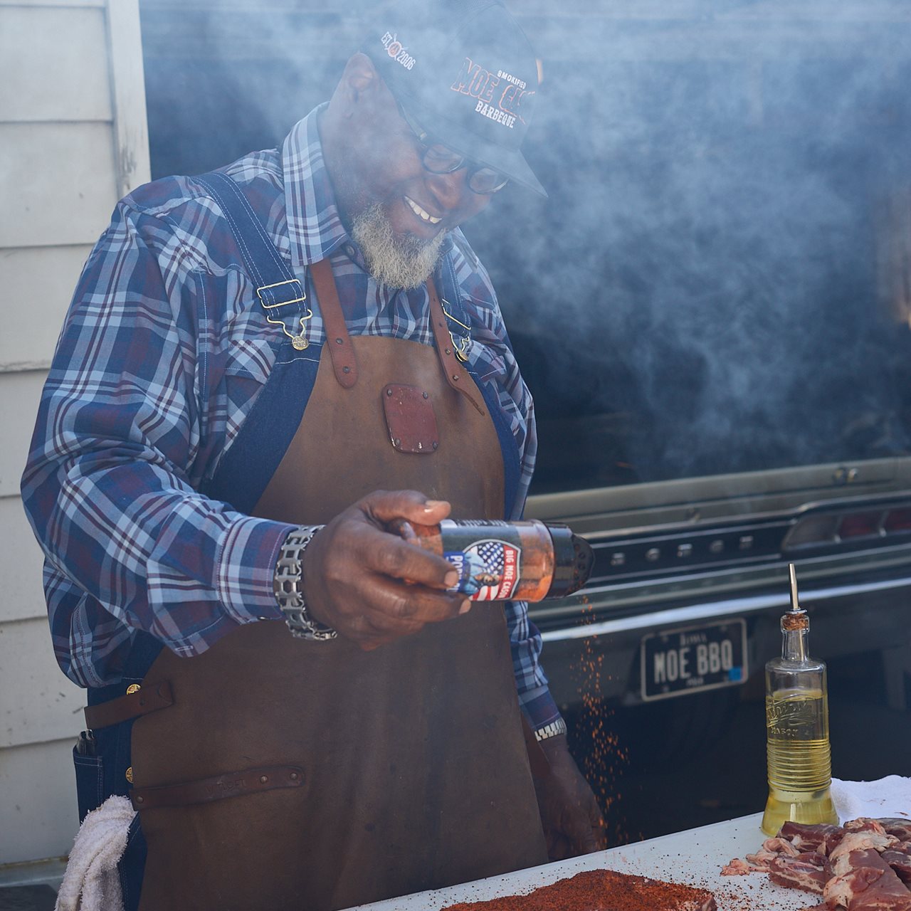 Big Moe preparing ribs inf front of a smokey grill.