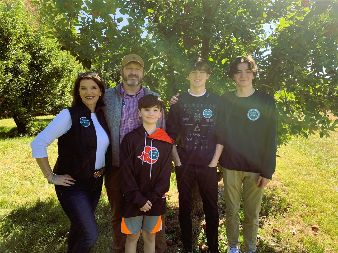 Jen, her husband and her three sons in an apple orchard.