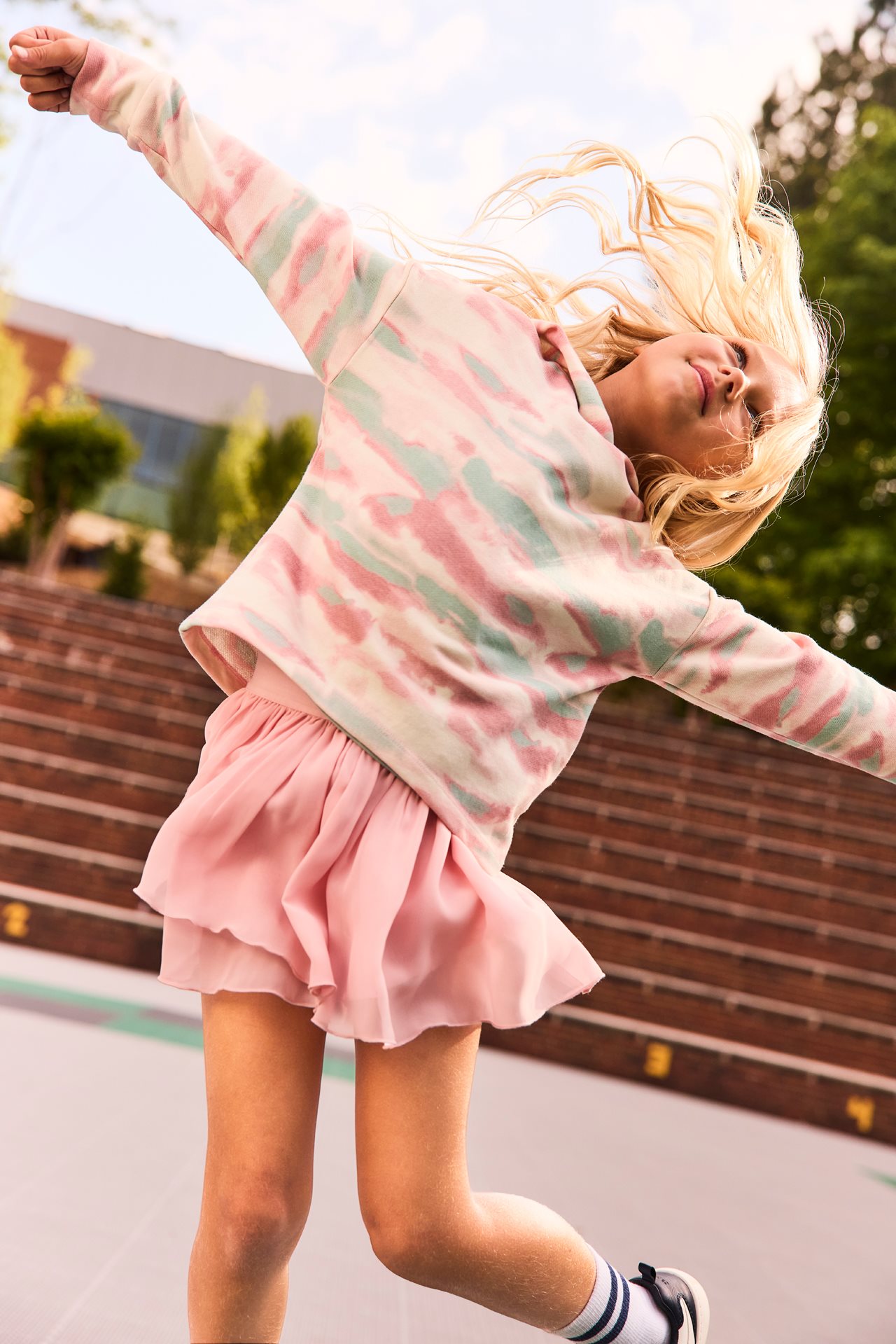 Happy girl wearing a new sweater and skirt spinning around on the playground.