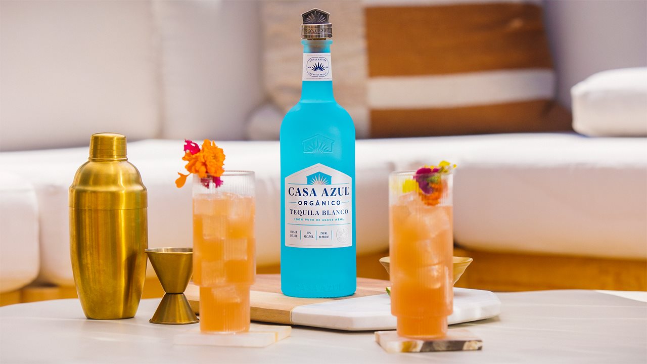 Bottle of casa azul with drink glasses and a shaker on a tray in the livingroom.