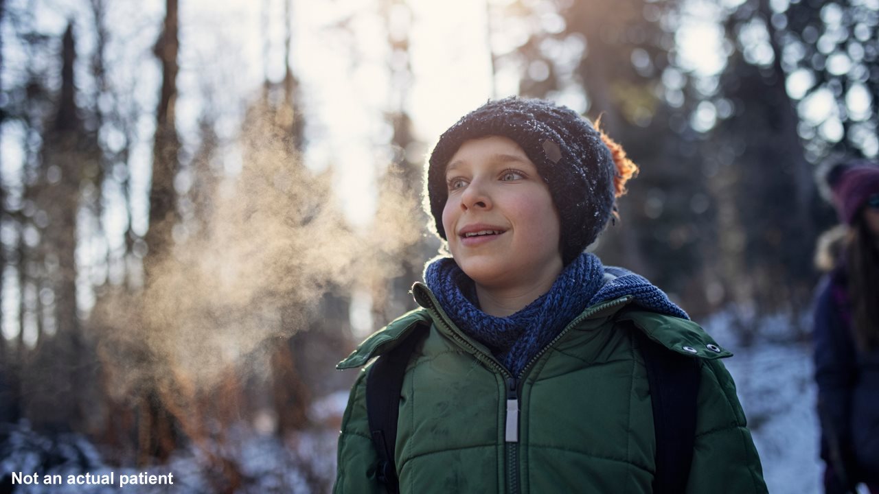 Young boy wearing winter gear and hiking in the woods