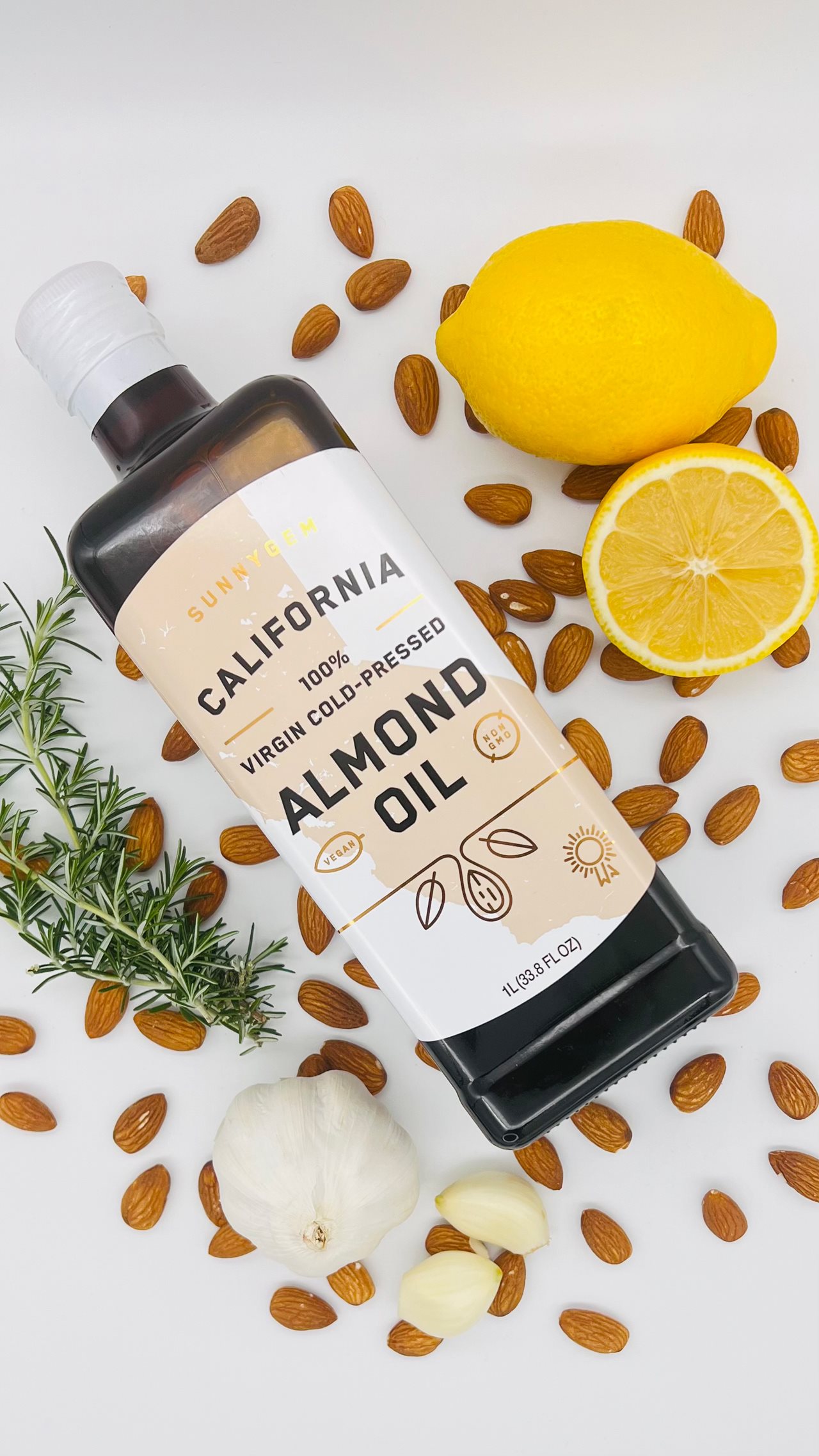 Close up of California Almond Oil bottle on a counter top with almonds, lemons and sprig of rosemary.