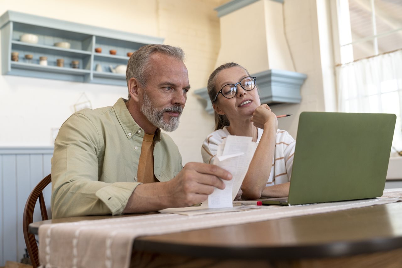 Parents of college student working on budget while on laptop in the kitchen.