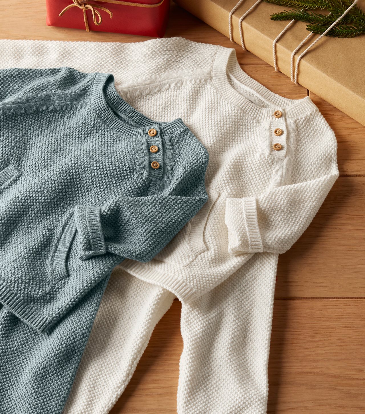 A pair of cozy knit sweaters laying out near the firplace hearth.