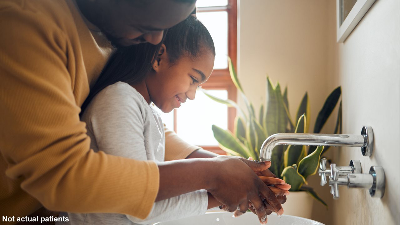 Dad helping little girl wash her hands in the bathroom sink.