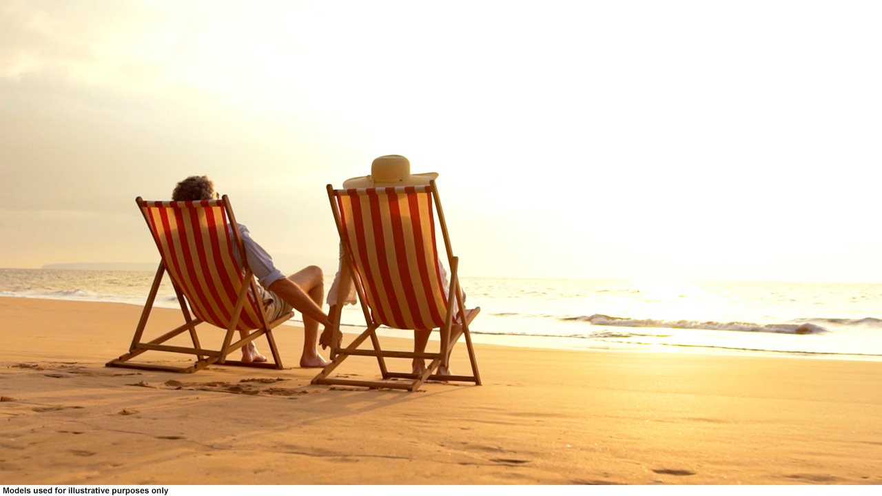 Couple holding hands and relaxing on the beach while sitting in foldable chairs.