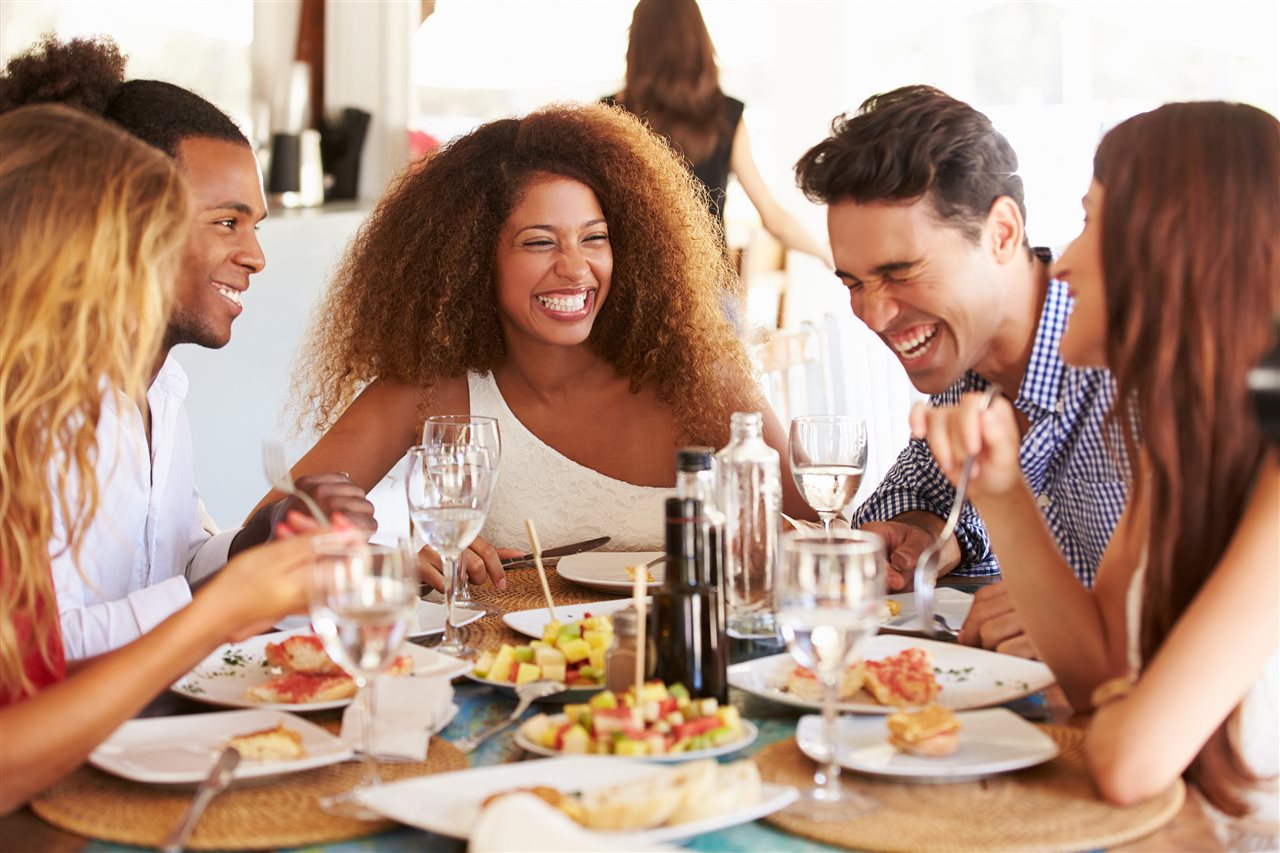 Group of friends laughing and enjoying lunch together in a cafe