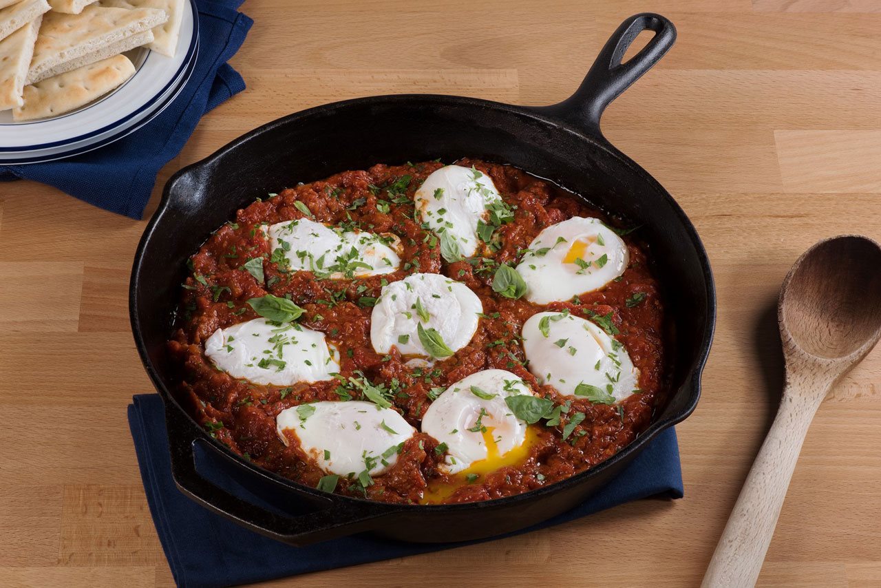 Marinara shakshuka in a cast iron pan with bread on the side.