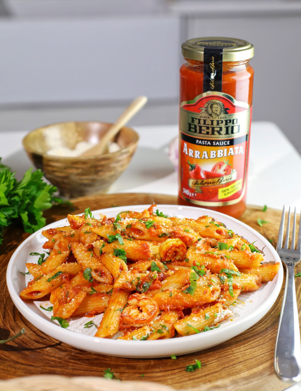 Plate of penne arrabbbiata with prawns with a jar of Fillippo Berio jar on countertop