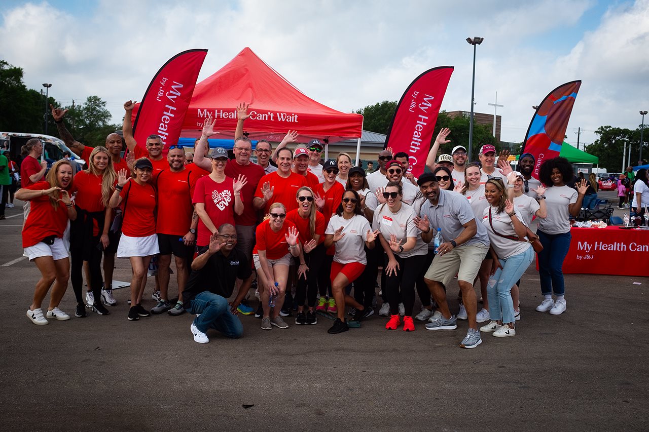 Large group of happy people, many dressed in red, enjoying an outdoor event.