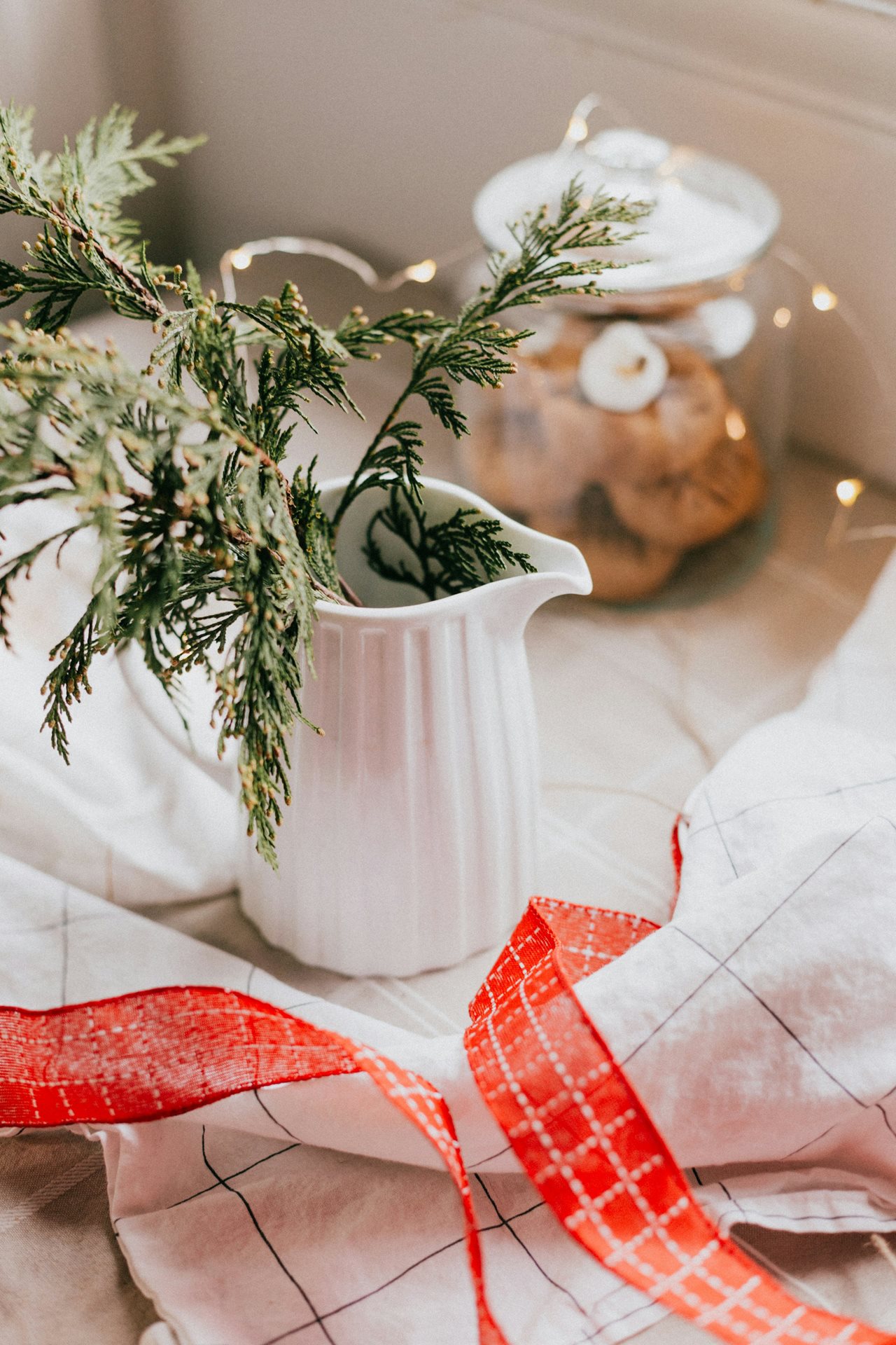 Holiday pitcher with greens on a table.