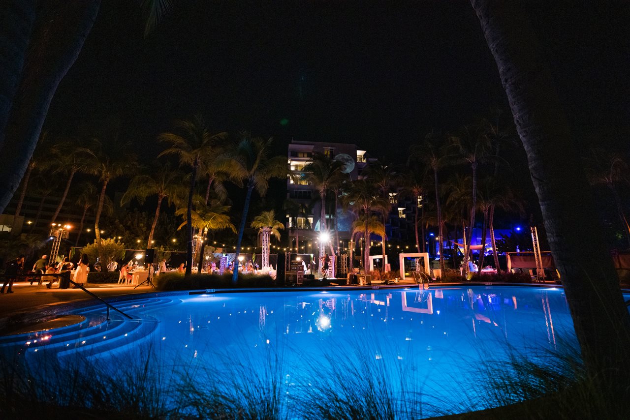 Friends enjoying outdoor dinner and cocktails at night poolside at the Aruba Hilton