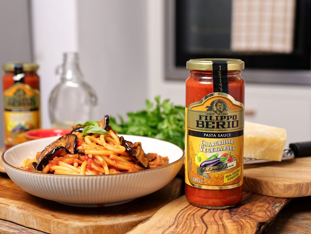 Bowl of grilled vegetable spaghetti alla norma with a jar of Filippo Berio grilled vegetables.