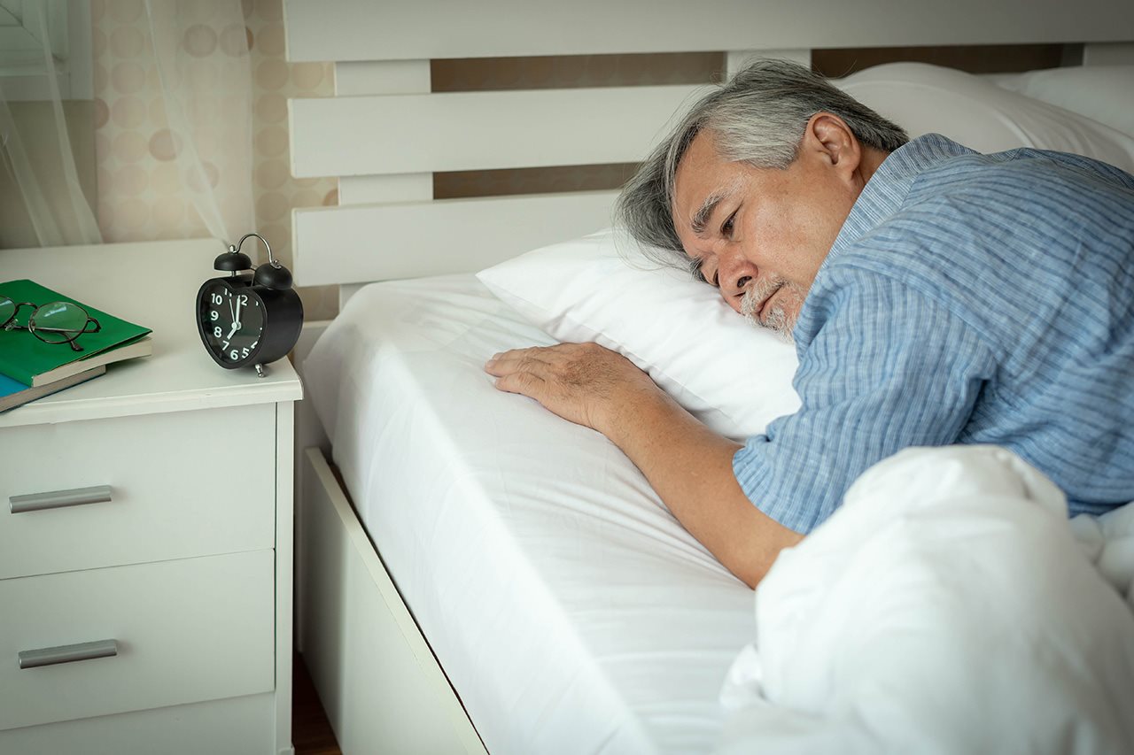 Older man laying awake in bed.