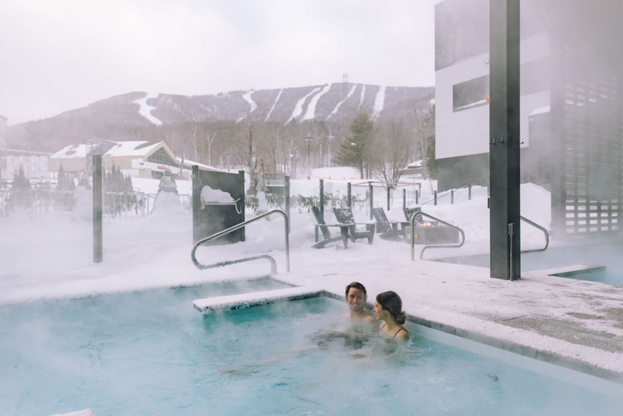 Cozy couple relaxing in a hot-tub outside in Winter outside their room in the Delta hotel by Marriott Mont Sainte Anne.